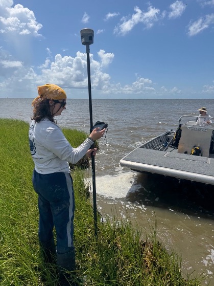 scientist standing on a shoreline holding a scientific instrument